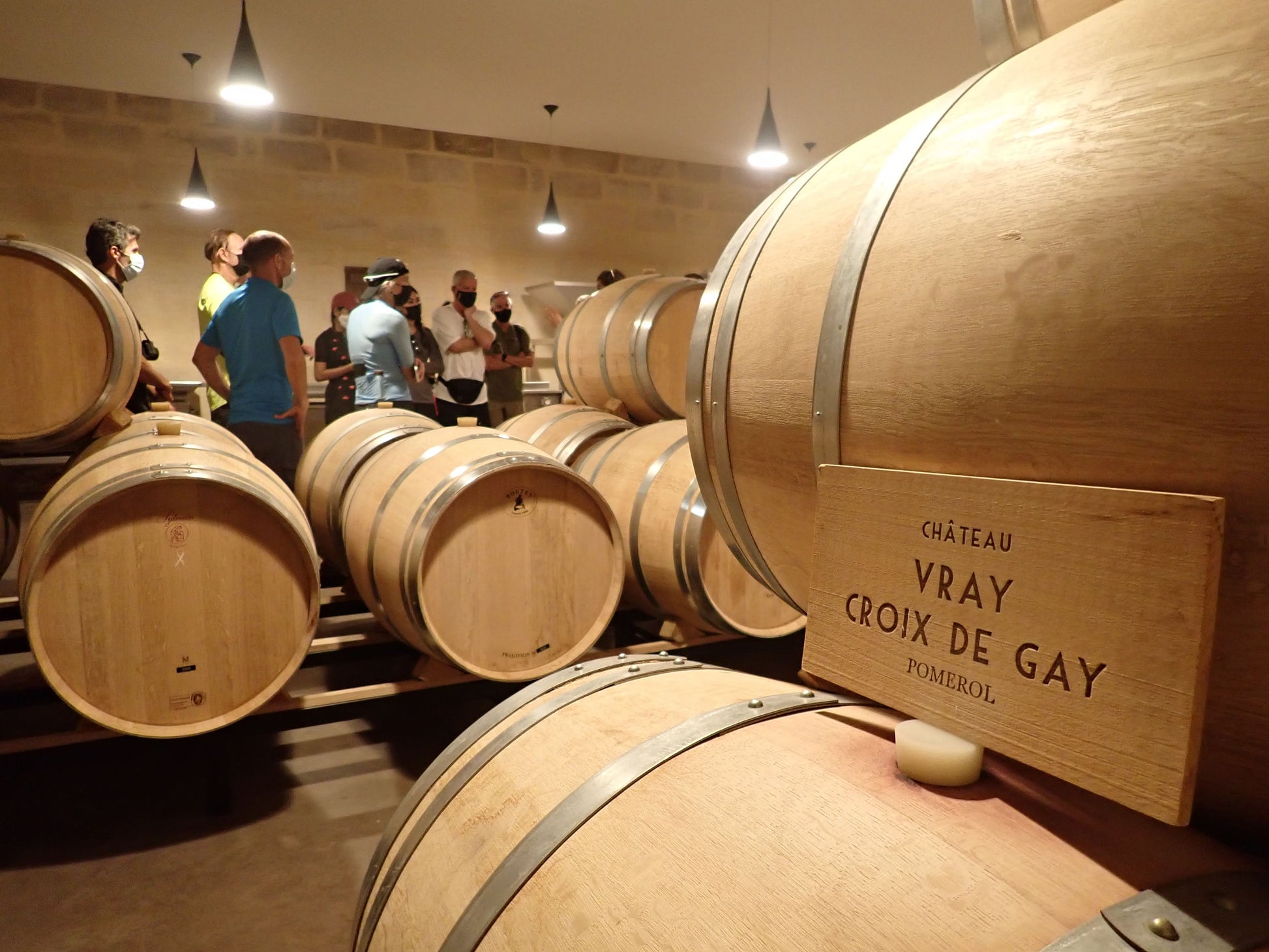 People explore a wine cellar with large oak barrels on the Dordogne Bike Tour.