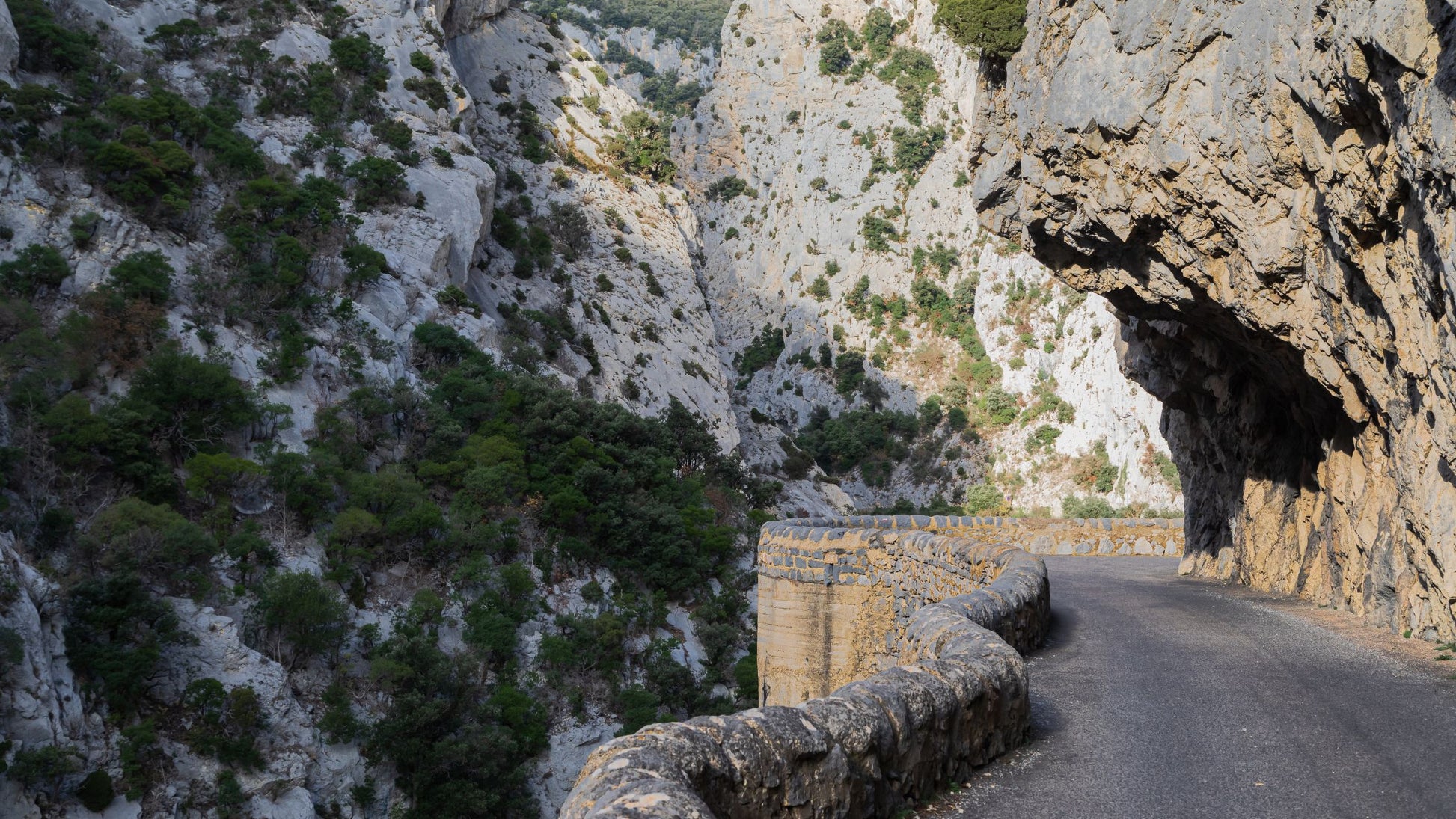 The Languedoc Occitania Bike Tour by cttc-4e8f features a narrow mountain road winding along rugged cliffs.
