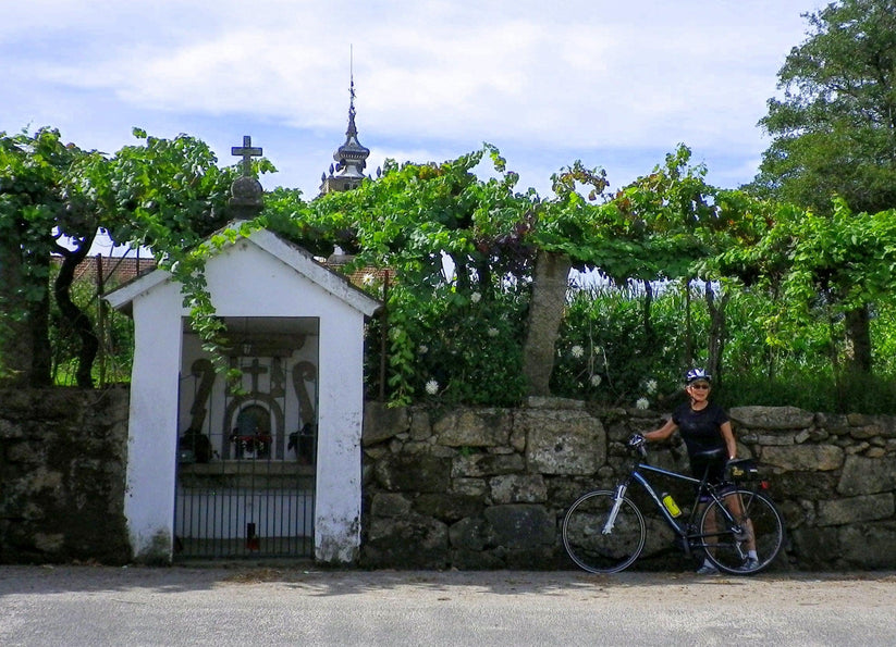 Female cyclist stopped by a granite church in the Minho region in Portugal