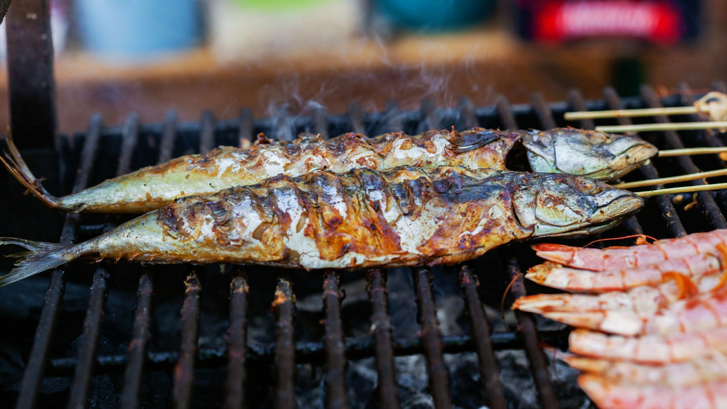 Two are grilling fish and shrimp over smoky barbecue. Algarve Bike Tour brings you local flavors and adventure.