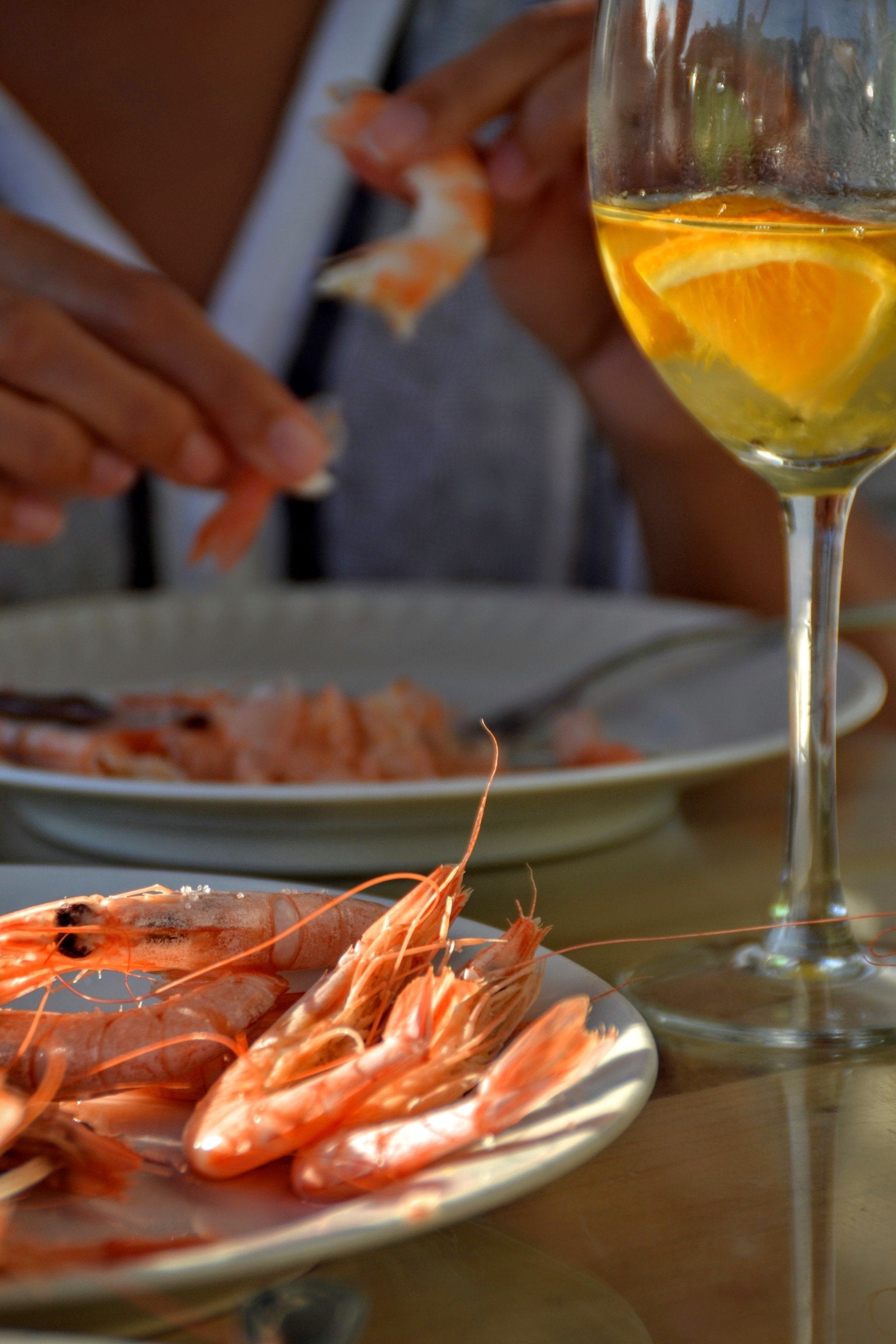 A person enjoys an Algarve Bike Tour, peeling shrimp with orange-infused drinks at the table.